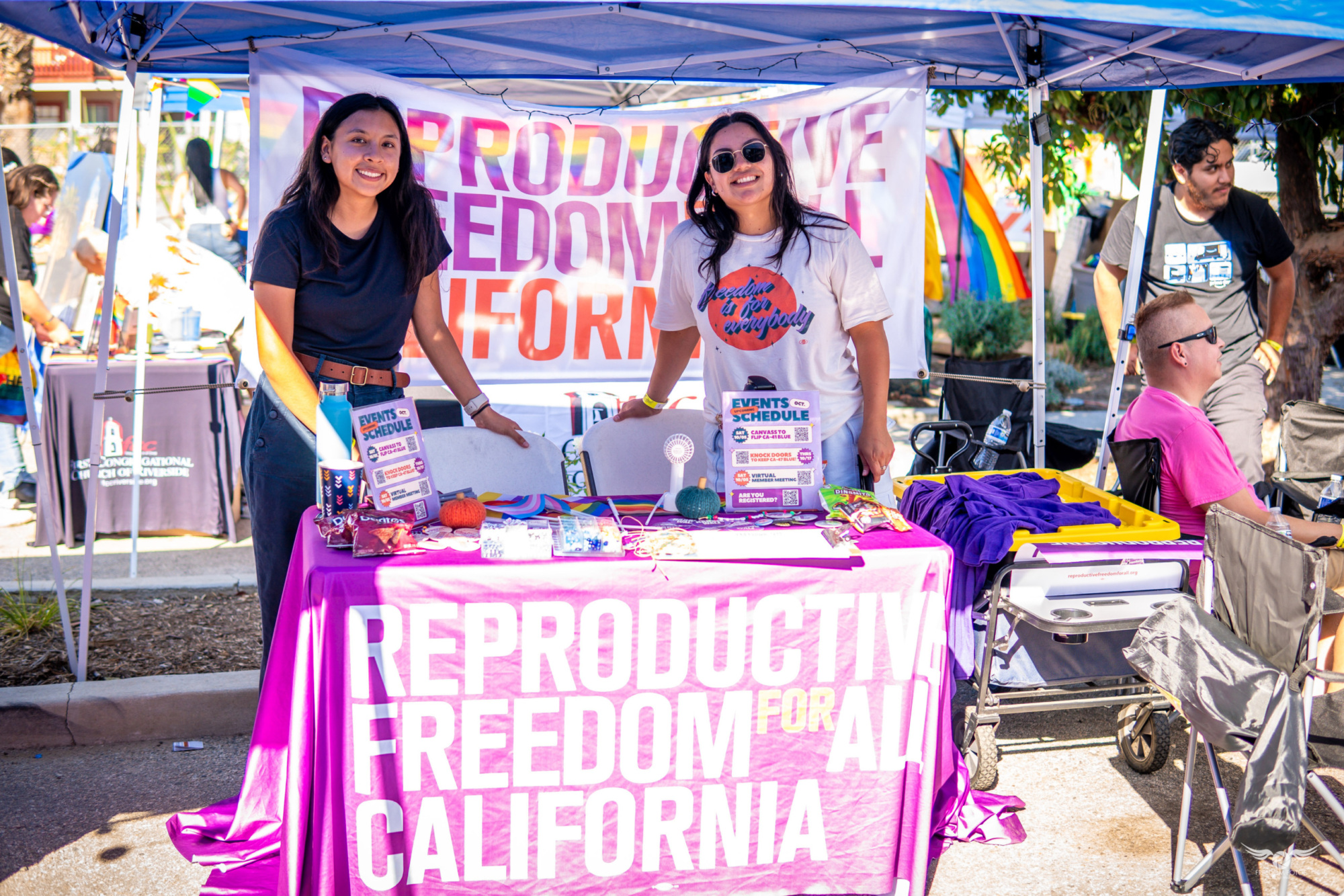 Two people standing at a table with Reproductive Freedom for All California banner